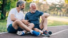 Two seniors relax on a track with Apple smart devices