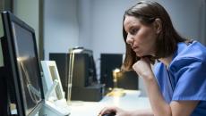 A doctor looking at imaging results on a desktop computer.