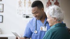 A doctor looking at a tablet with a patient.