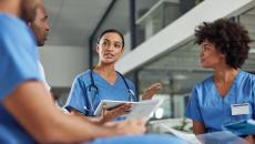 Four people in nursing uniforms, one wearing stethoscope 