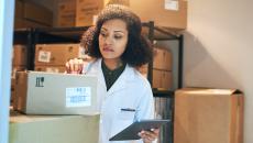 A person using a digital tablet while doing inventory in the storeroom of a pharmacy