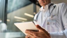 A doctor holding a digital tablet reviewing a patient's record