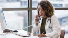 Healthcare provider on the phone while sitting at a desk with a computer on it 