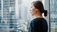 A woman holding a smartphone staring out the window