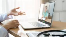 Healthcare provider sitting at a desk with a computer on it and a person on the screen