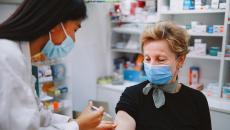 Person sitting in a pharmacy and getting an injection by a pharmacist