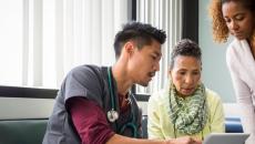 Healthcare professional discusses with two people over a laptop