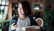 Person smiling while in their home and holding a phone with boxes around them 