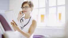 Healthcare provider with a stethoscope around their neck while holding a tablet