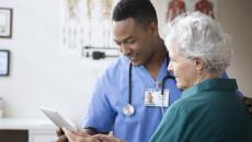 Healthcare provider talking to a patient while showing them a tablet