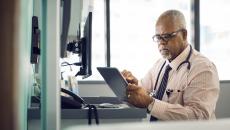 Healthcare provider sitting at a desk and looking at a tablet