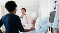 A doctor talking to patient and his family in a hospital room.