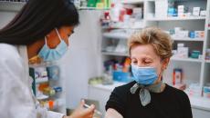 An older person receiving a vaccine in a pharmacy.