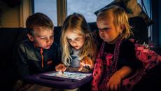 Three children playing on a digital tablet