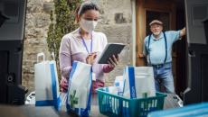 A woman wearing a mask delivering medications. 