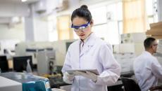 A researcher in a lab looking at a tablet