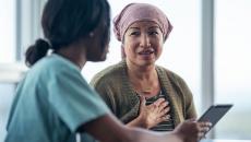 Healthcare provider sitting next to a patient while both look at a tablet