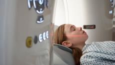 Person lying just outside an MRI machine with a red scanning light on their face