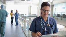 Healthcare provider looking at a tablet in the hallway of a large building