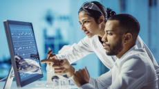 Two healthcare professionals at a desk while looking at a computer screen