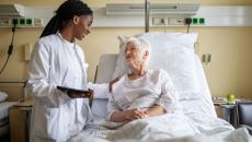 Healthcare provider standing next to a patient lying in a bed in a hospital room