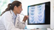 Healthcare provider sitting down and looking at a computer screen with diagnostic images on it