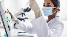 Person wearing mask holding test tube