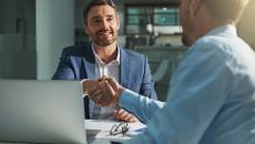 Two people sitting across from each other and shaking hands