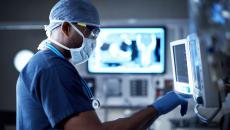 Healthcare provider in scrubs looking at computer screens