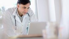 A doctor using a laptop to write referrals
