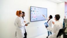 Four healthcare providers in a room looking at a screen with data on it