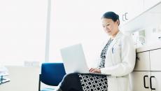 A doctor using a laptop to review a patient's file