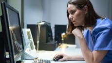 A clinician reading a report from a desktop computer.