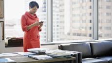 A woman at her desk looking down at her smartphone